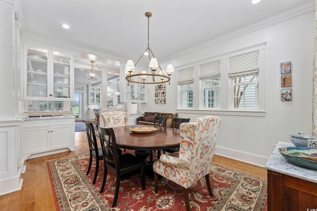 dining area featuring wood-type flooring, a chandelier, and crown molding