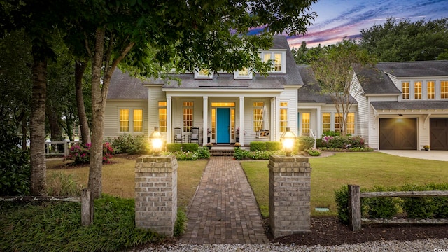 view of front of house with a porch, a yard, and a garage