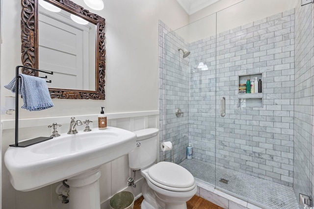 bathroom with a shower with shower door, toilet, and sink