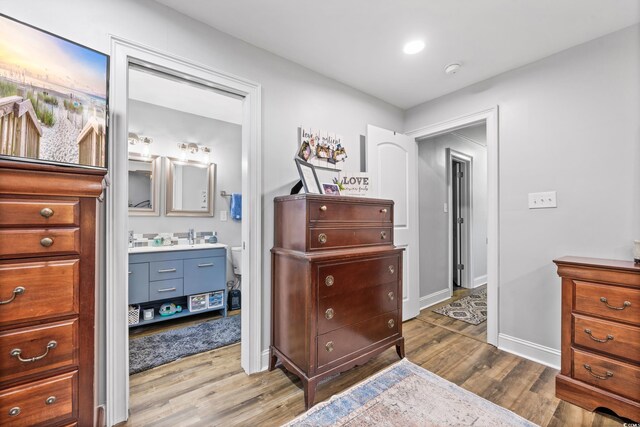 bedroom with ensuite bathroom and hardwood / wood-style floors