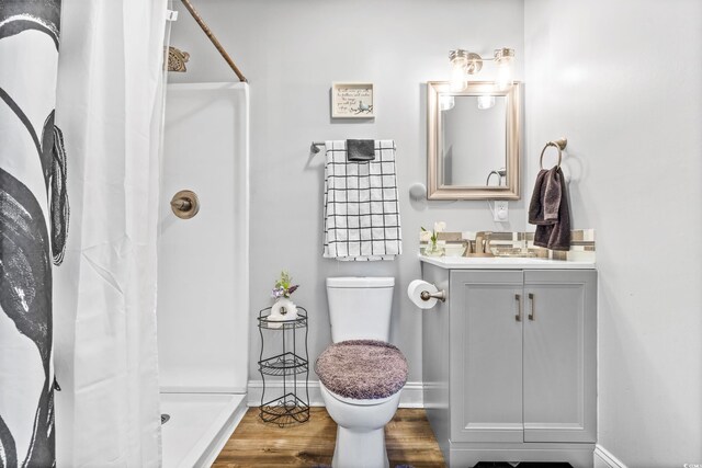 bathroom featuring toilet, hardwood / wood-style floors, a shower with curtain, and vanity