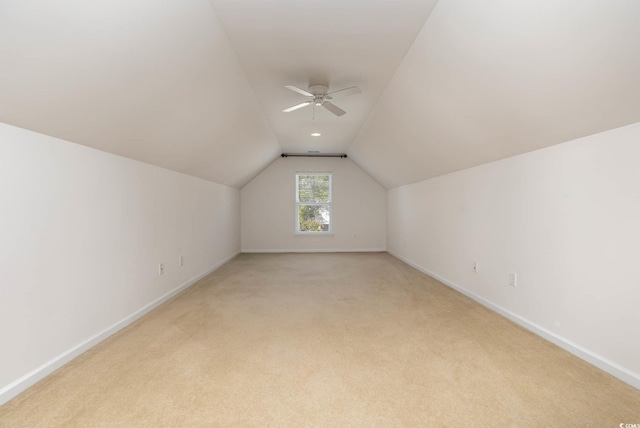 additional living space featuring vaulted ceiling, light carpet, baseboards, and a ceiling fan