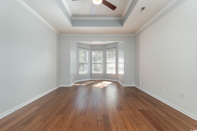 spare room featuring a ceiling fan, dark wood-type flooring, baseboards, a raised ceiling, and visible vents