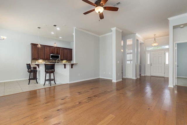 unfurnished living room with light wood-type flooring, ceiling fan, and crown molding