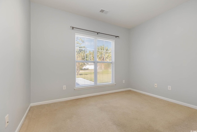 unfurnished room featuring baseboards, light carpet, and visible vents