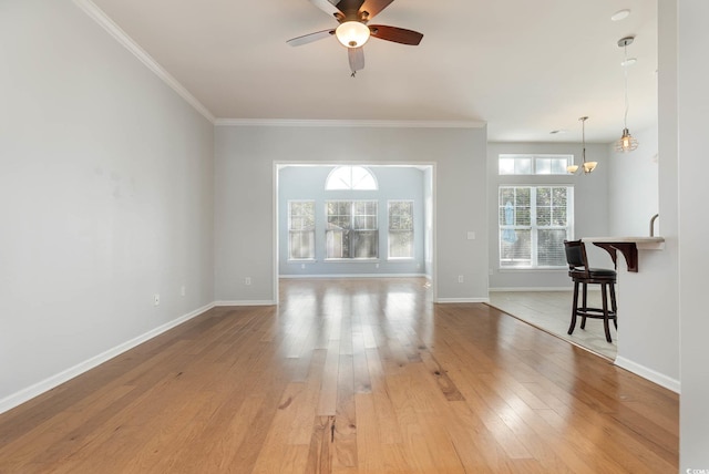unfurnished living room with baseboards, ornamental molding, light wood-style flooring, and ceiling fan with notable chandelier