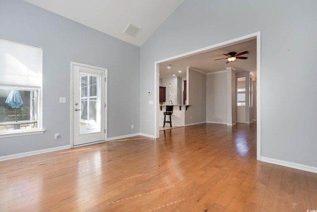 unfurnished room with baseboards, high vaulted ceiling, visible vents, and light wood-style floors