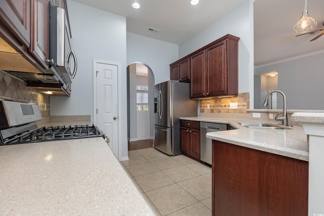 kitchen with a sink, a peninsula, arched walkways, backsplash, and appliances with stainless steel finishes