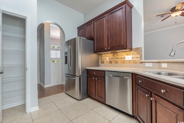 kitchen featuring ceiling fan, a sink, arched walkways, stainless steel appliances, and tasteful backsplash
