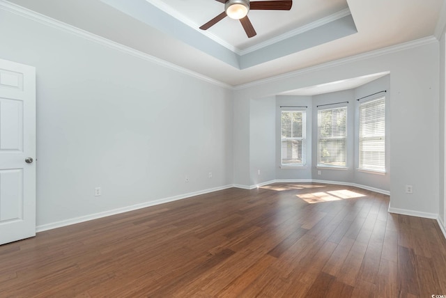 unfurnished room with baseboards, dark wood-style flooring, ornamental molding, ceiling fan, and a raised ceiling