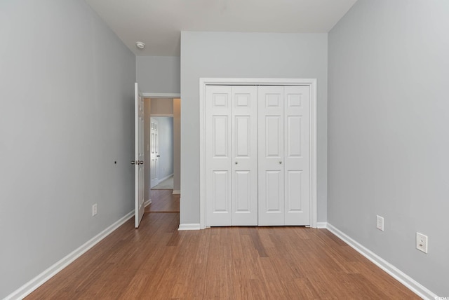 unfurnished bedroom with baseboards, a closet, and wood finished floors