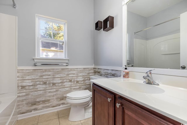 bathroom featuring tile walls, toilet, tile patterned flooring, vanity, and a wainscoted wall