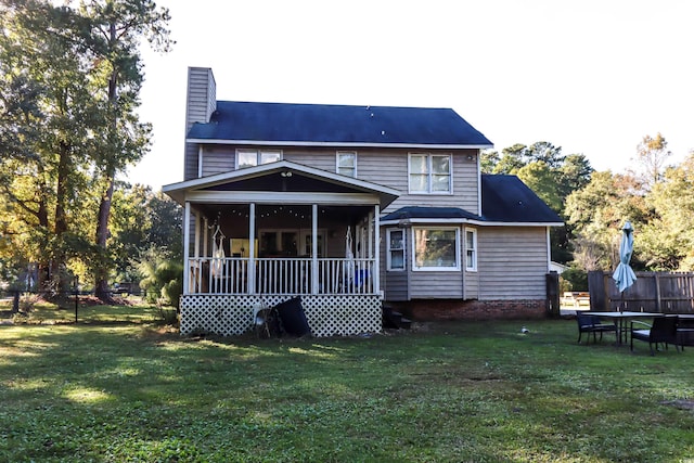 rear view of property featuring a lawn and a sunroom