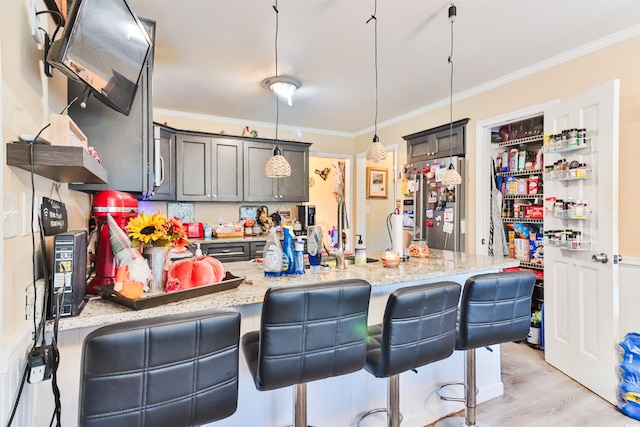 kitchen featuring light stone countertops, hanging light fixtures, crown molding, light hardwood / wood-style floors, and a breakfast bar area