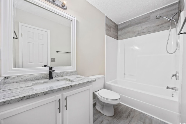 full bathroom with tub / shower combination, vanity, a textured ceiling, hardwood / wood-style floors, and toilet