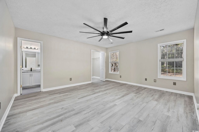 unfurnished bedroom with light wood-type flooring, connected bathroom, multiple windows, and ceiling fan