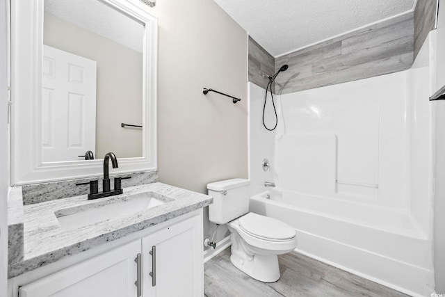 full bathroom featuring hardwood / wood-style floors, vanity, tiled shower / bath combo, toilet, and a textured ceiling