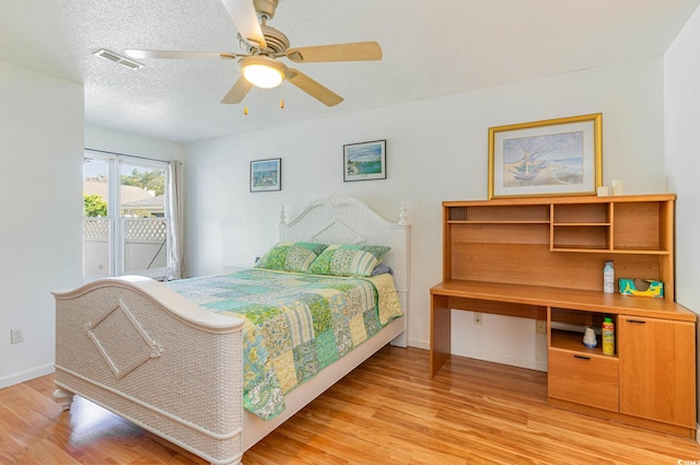 bedroom featuring light hardwood / wood-style flooring, a textured ceiling, access to exterior, and ceiling fan