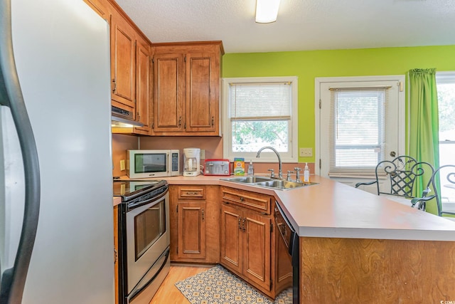 kitchen with stainless steel electric stove, kitchen peninsula, sink, refrigerator, and light hardwood / wood-style floors