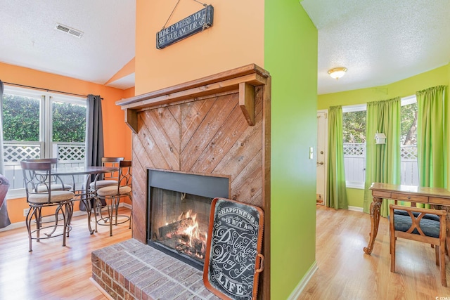 interior space featuring a textured ceiling, a brick fireplace, and hardwood / wood-style flooring