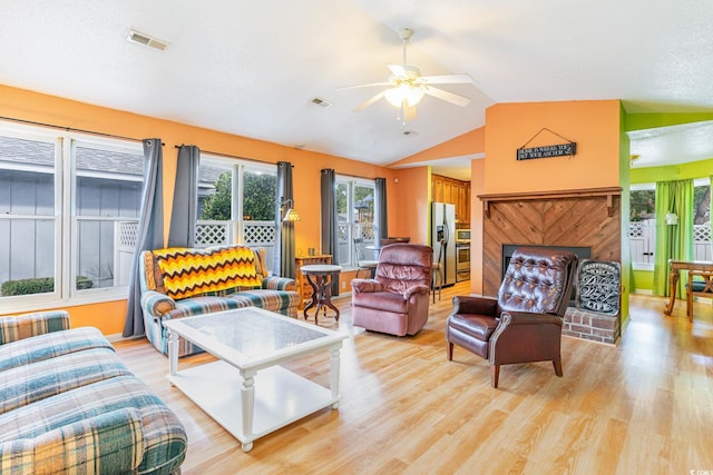 living room with ceiling fan, lofted ceiling, and light wood-type flooring