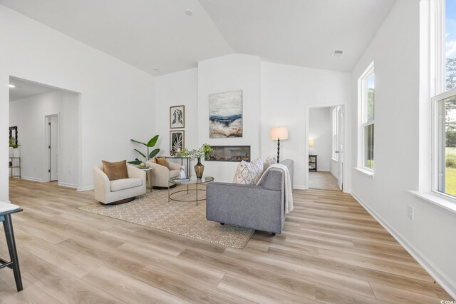 living room with baseboards, visible vents, high vaulted ceiling, and light wood-style floors