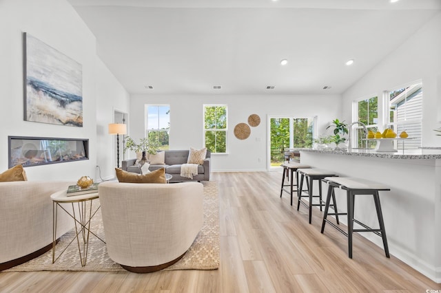 living room with recessed lighting, lofted ceiling, visible vents, and light wood-type flooring