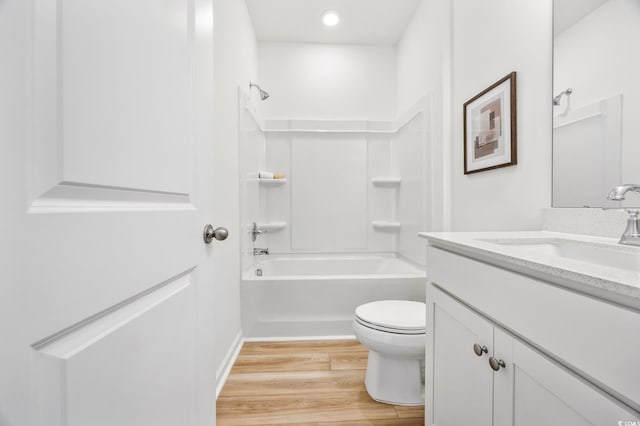 bathroom with wood finished floors, vanity, shower / bath combination, baseboards, and toilet