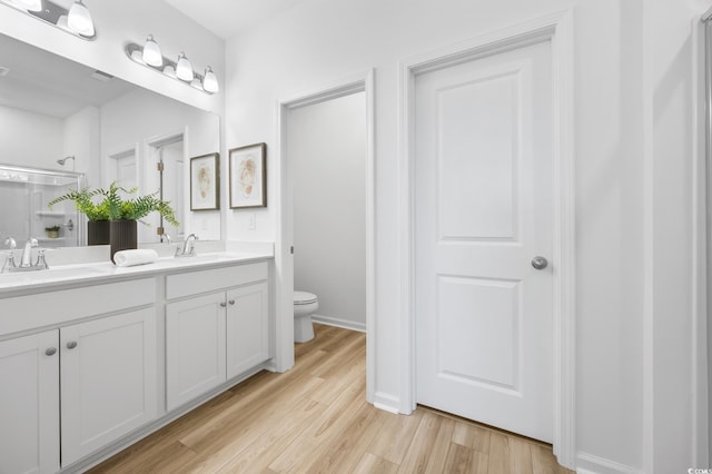 bathroom with vanity, toilet, wood-type flooring, and an enclosed shower