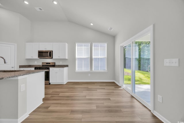 389 Sun Colony Blvd, Longs, SC 29568 - kitchen featuring appliances with stainless steel finishes, lofted ceiling, white cabinetry, light wood-type flooring, and dark stone counters