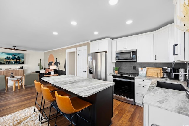 kitchen featuring dark wood-type flooring, sink, a center island, white cabinets, and appliances with stainless steel finishes