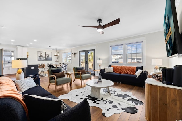 living room with crown molding, light wood-type flooring, and ceiling fan