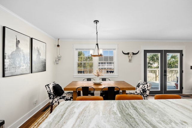 dining room featuring french doors, hardwood / wood-style flooring, ornamental molding, and an inviting chandelier