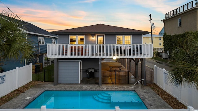 back house at dusk with a patio area and a swimming pool side deck