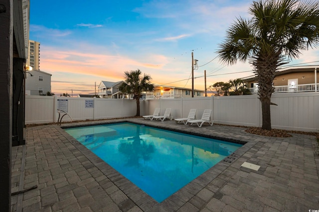 pool at dusk featuring a patio area