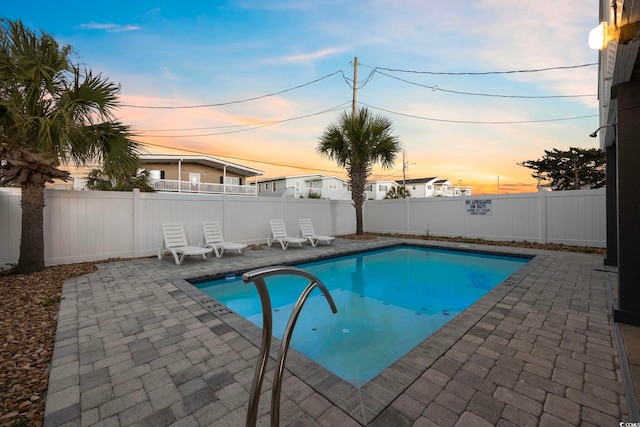 pool at dusk featuring a patio