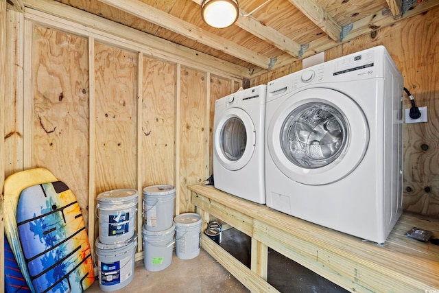 laundry room featuring wood walls and washing machine and dryer