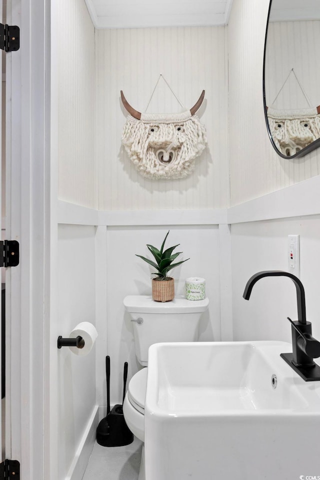 bathroom featuring toilet, crown molding, and sink