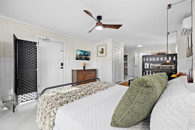 bedroom featuring ceiling fan, crown molding, a wall mounted AC, and ensuite bath