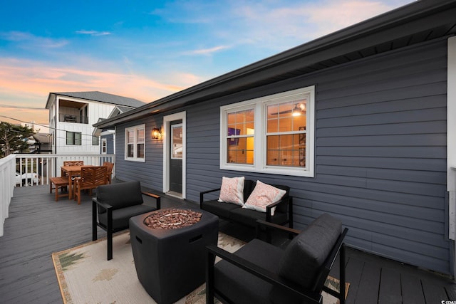 deck at dusk with an outdoor living space with a fire pit