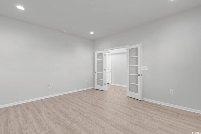 spare room featuring french doors and light hardwood / wood-style floors