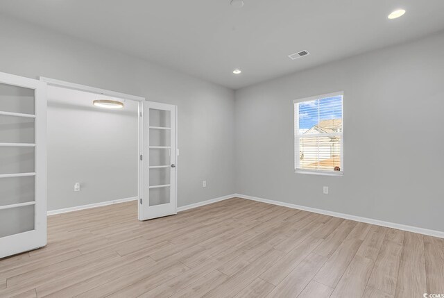 spare room featuring french doors, light hardwood / wood-style floors, and built in shelves