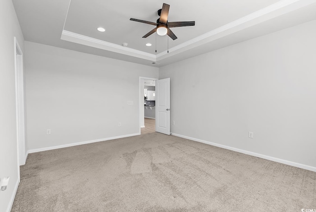 empty room featuring carpet, ceiling fan, and a tray ceiling