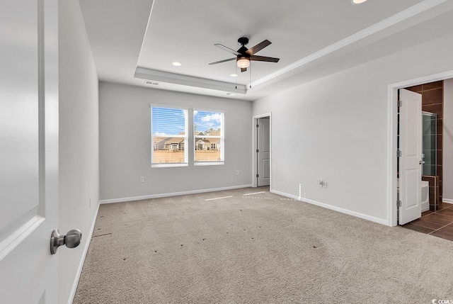 carpeted spare room featuring a raised ceiling and ceiling fan