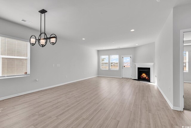 unfurnished living room featuring light hardwood / wood-style floors and a notable chandelier