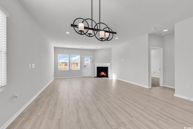 unfurnished living room with light hardwood / wood-style floors and an inviting chandelier