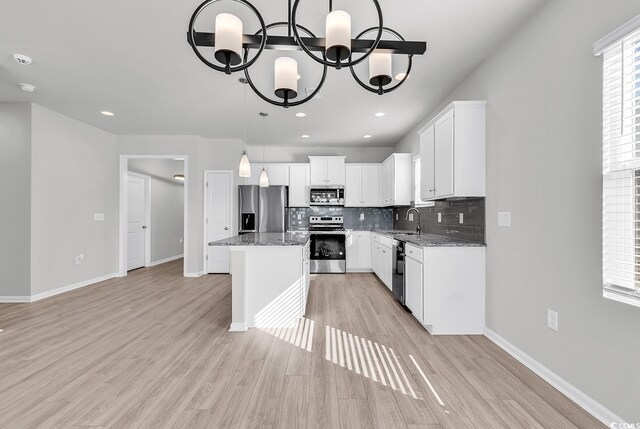 kitchen featuring stainless steel appliances, a notable chandelier, white cabinets, and a center island