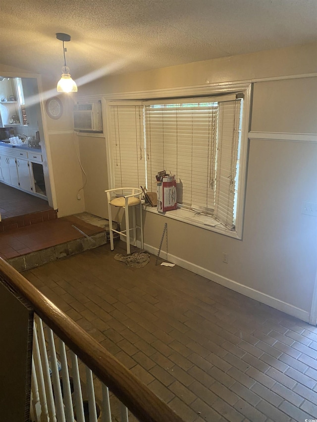 interior space with a wall mounted air conditioner and a textured ceiling