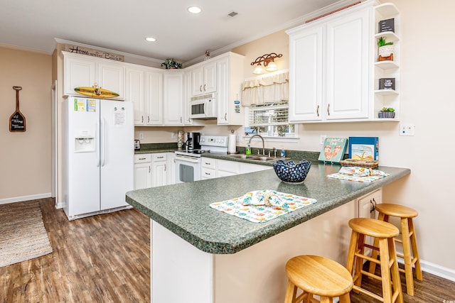 kitchen featuring white appliances, sink, dark hardwood / wood-style flooring, kitchen peninsula, and white cabinetry