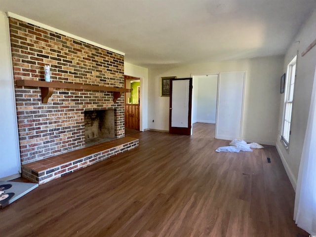 unfurnished living room with dark hardwood / wood-style floors and a brick fireplace